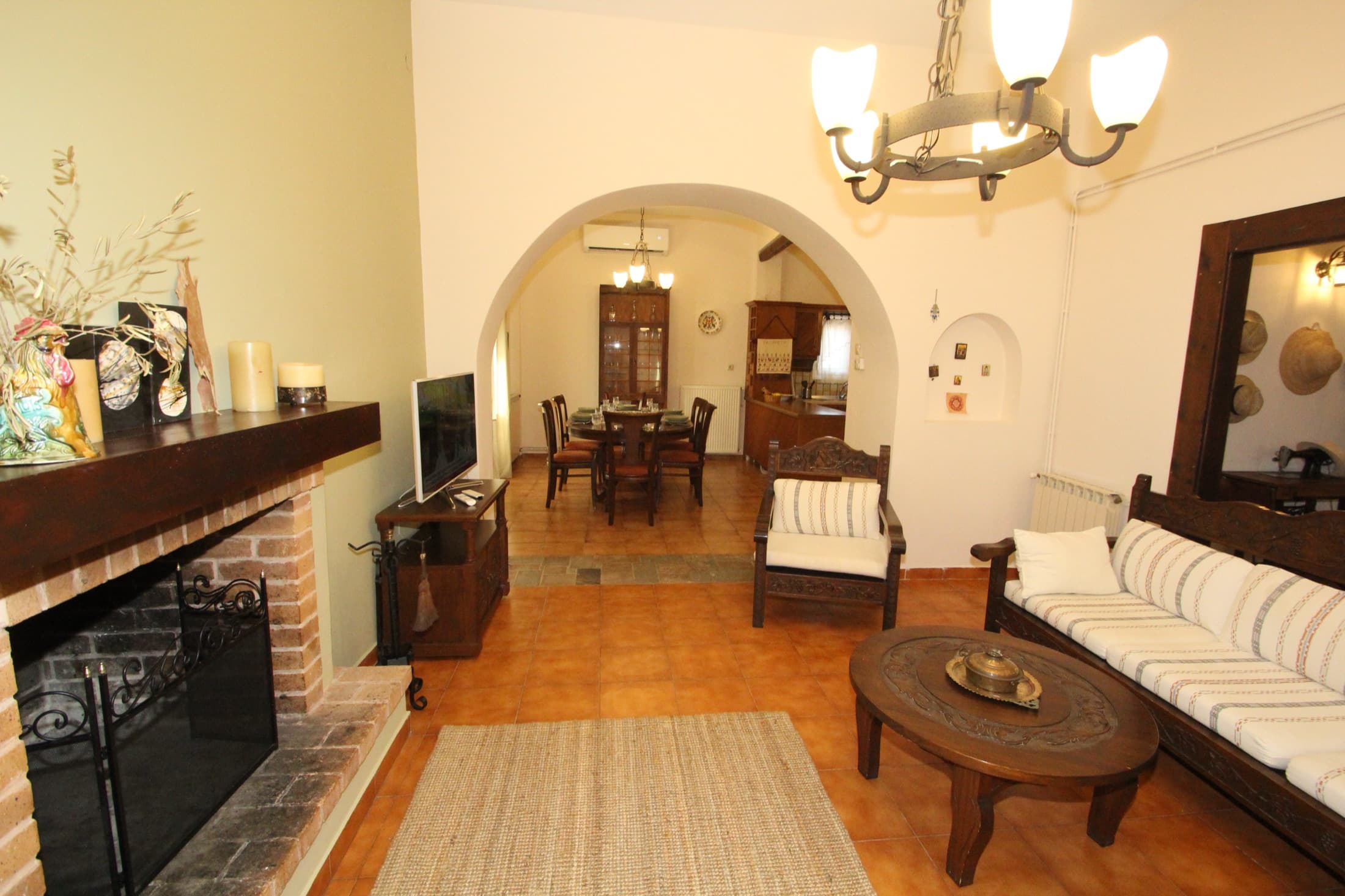 Living room at Fistiki House with a traditional fireplace and arch to the dining area